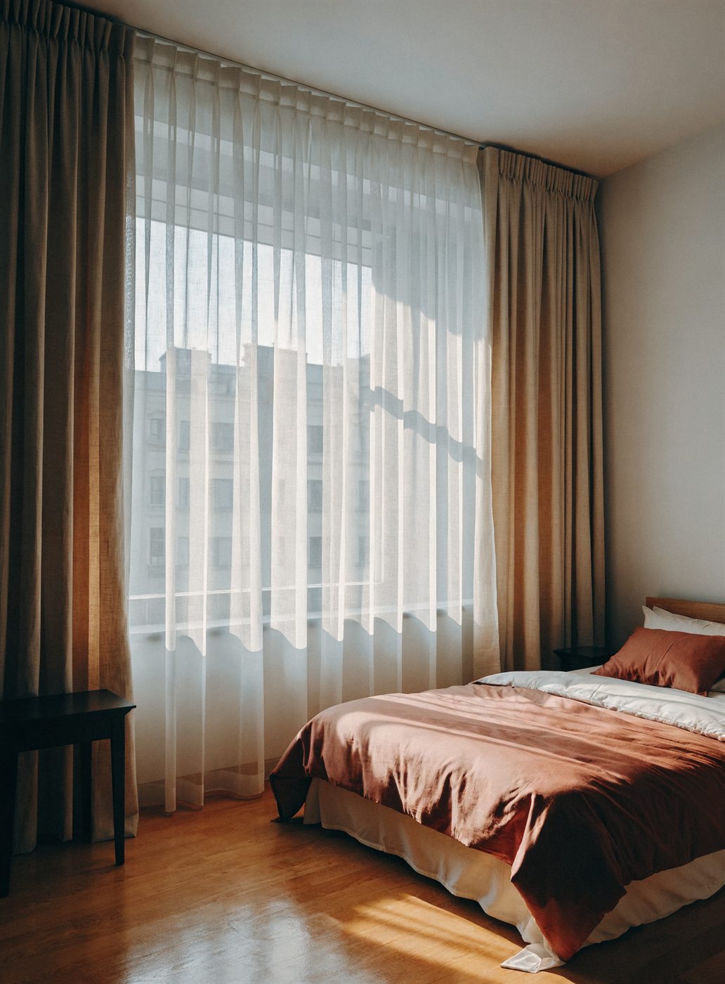 Dormitorio con cortinas de lino y voile en tonos cálidos, colocación a medida